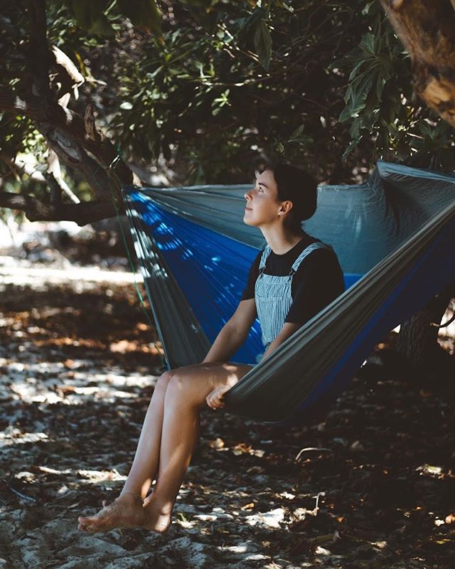 A woman relaxes in a hammock on the beach, enjoying a moment of peaceful solitude in nature.
