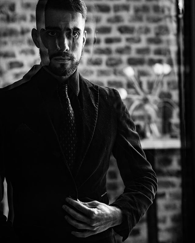 A man in a suit looks intensely at the camera in a black and white portrait.