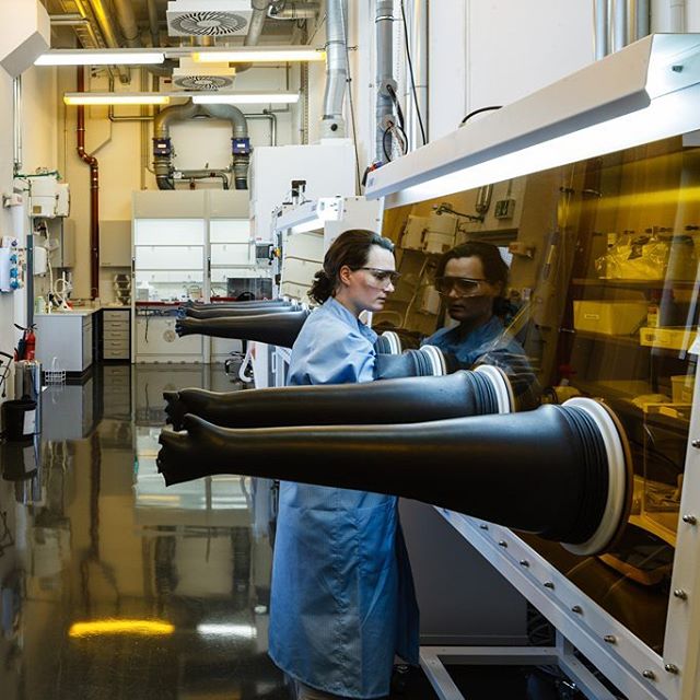 A scientist works inside a laboratory with a glove box.