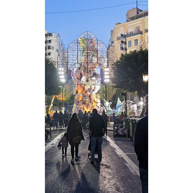 People enjoy an evening at a city event featuring a large sculpture under a blue sky.