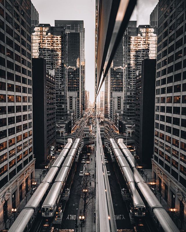 A symmetrical view of city streets with trains and towering buildings creating an urban landscape.