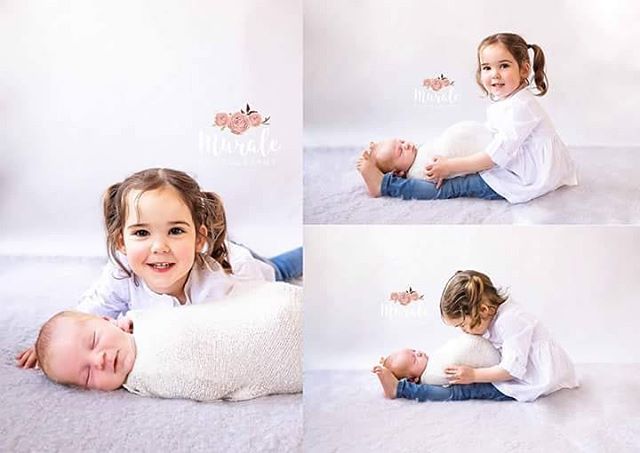 A sweet portrait shows a little girl lovingly interacting with her baby sibling in a studio setting.