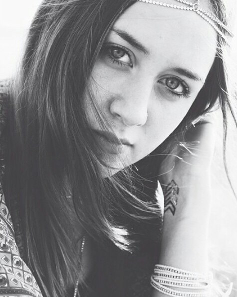 Portrait of a woman with a headband, arm tattoo, and bracelets in black and white.