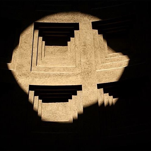 Abstract architectural design featuring geometric patterns highlighted by strong lighting and shadows.