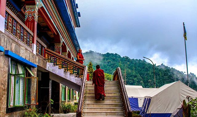 Two monks walk the stairs of a tranquil Buddhist monastery in the mountains on a cloudy day.