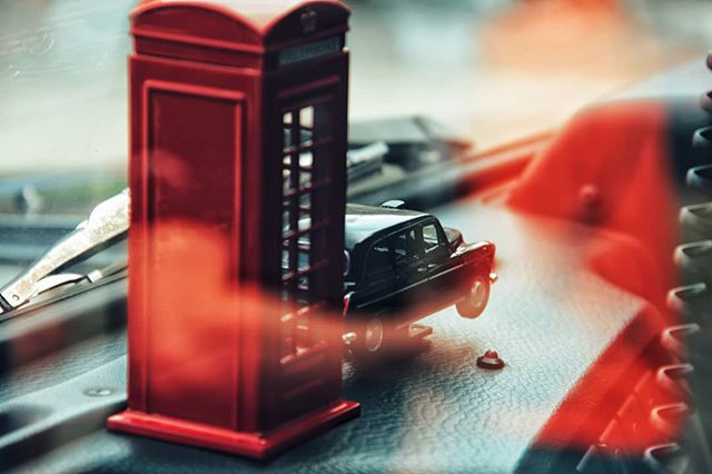 A miniature red telephone booth and a black taxi toy create a whimsical London scene.