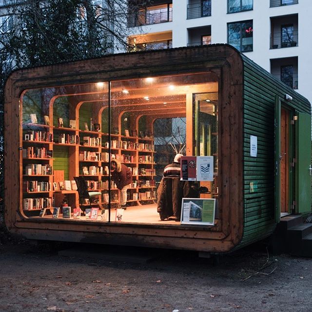A cozy, small bookstore with people browsing through shelves filled with books in an urban setting.