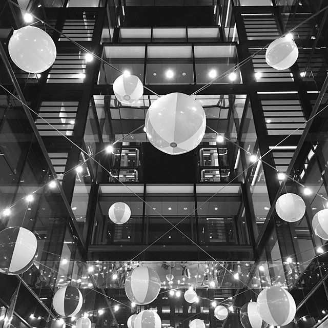 A low-angle shot showcases beach balls suspended within a modern building, creating a playful and abstract interior design.