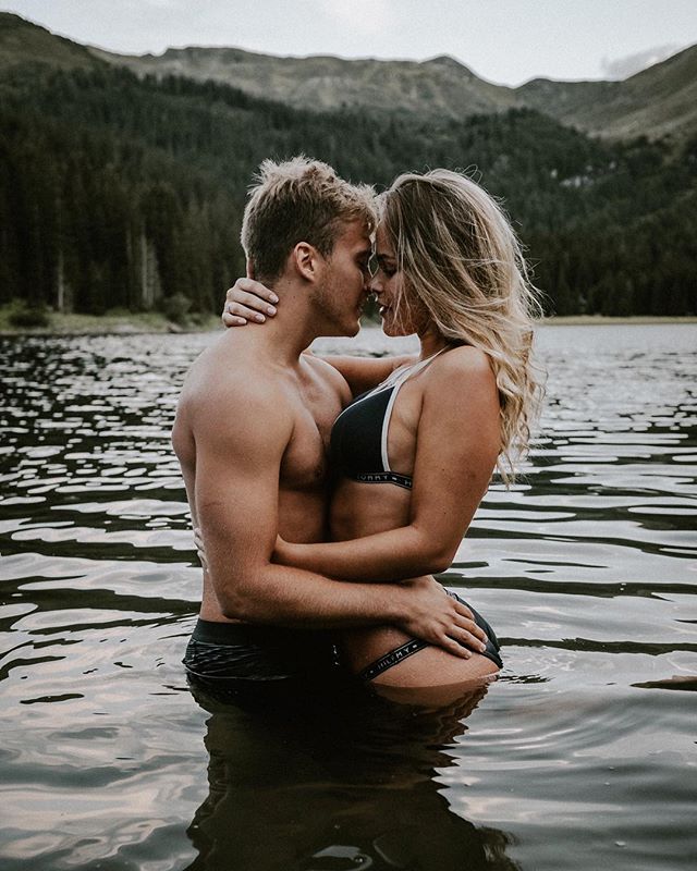 A loving couple embraces in a lake with a scenic mountain backdrop, perfect for romantic or fitness themed campaigns.