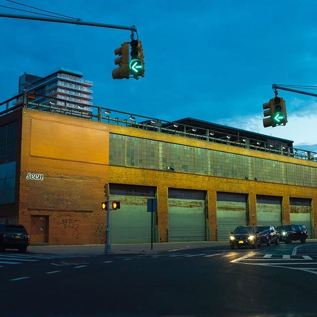 A cityscape featuring a building, traffic lights, and cars at a street corner.