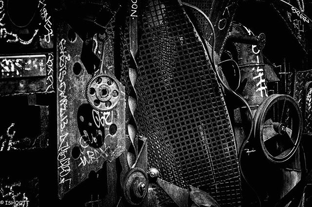 A high contrast, black and white close-up of an industrial metal sculpture with gears and abstract elements.