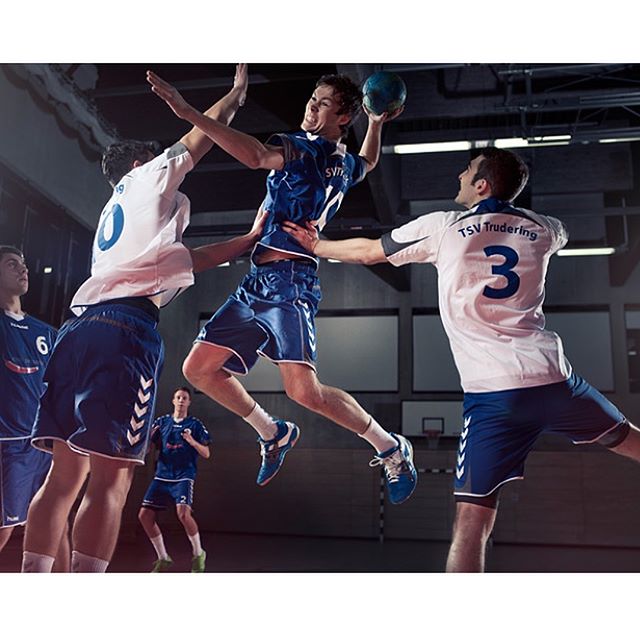 A dynamic shot of handball players in action during a game at an indoor court.