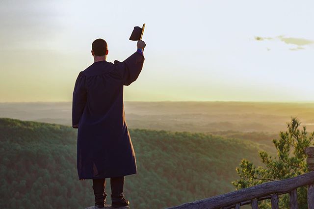 A graduate celebrates on a mountain top, symbolizing achievement and future opportunities. 