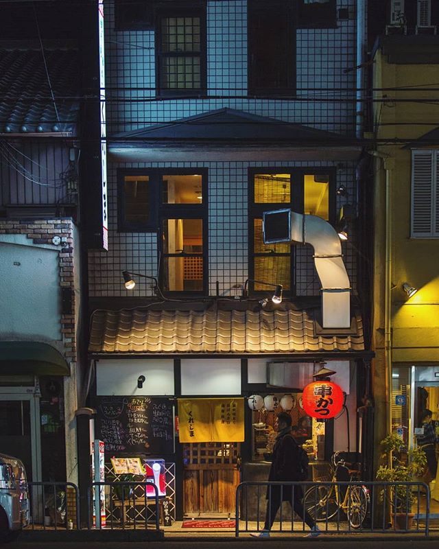 Exterior of a cozy restaurant with a red lantern in an urban city street at night.