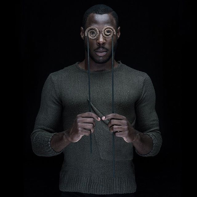 A man with spiral objects covering his eyes in a conceptual studio portrait against a black background.