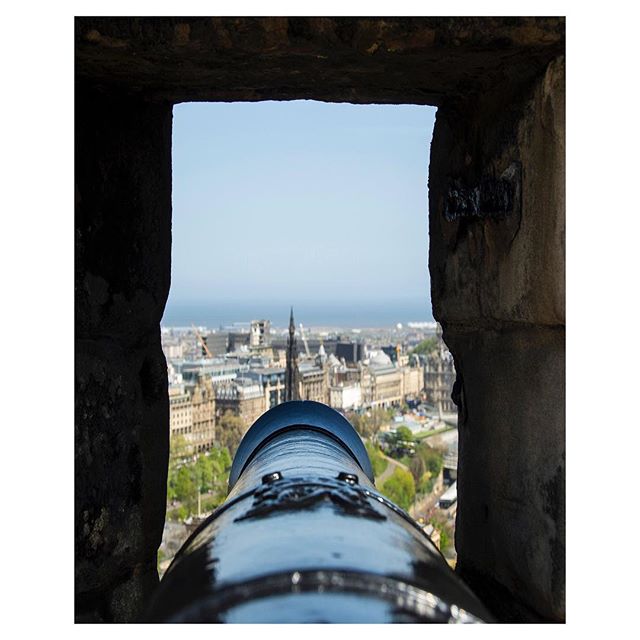 Cannon view through a stone window overlooking the cityscape and ocean, capturing a historical and scenic perspective.
