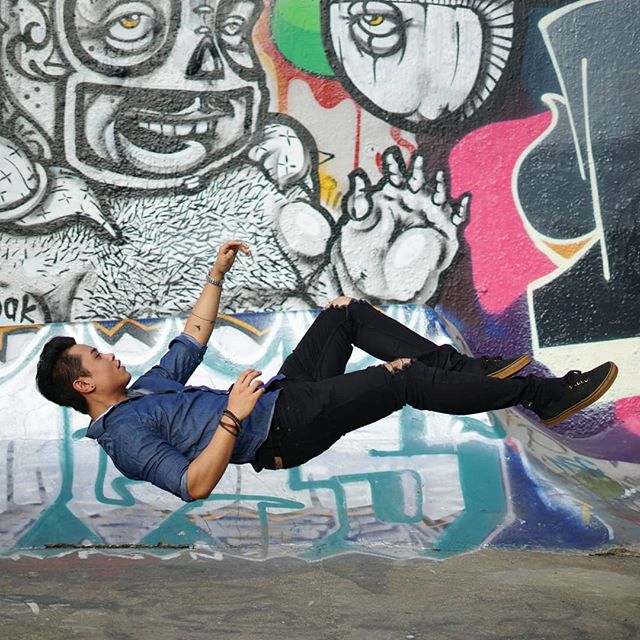 A man in a skate park floats mid-air with vibrant graffiti art in the background.