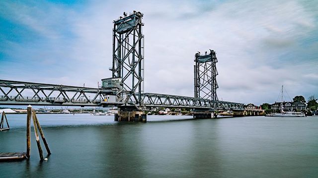 The bridge spans the calm waters of the river, connecting towns along the coast.