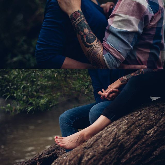 Intimate couple embraces by a river, showing their tattoos and connection in a natural setting.