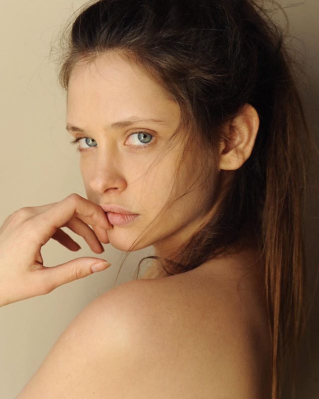 Intimate portrait of a young woman with blue eyes in soft, natural lighting.