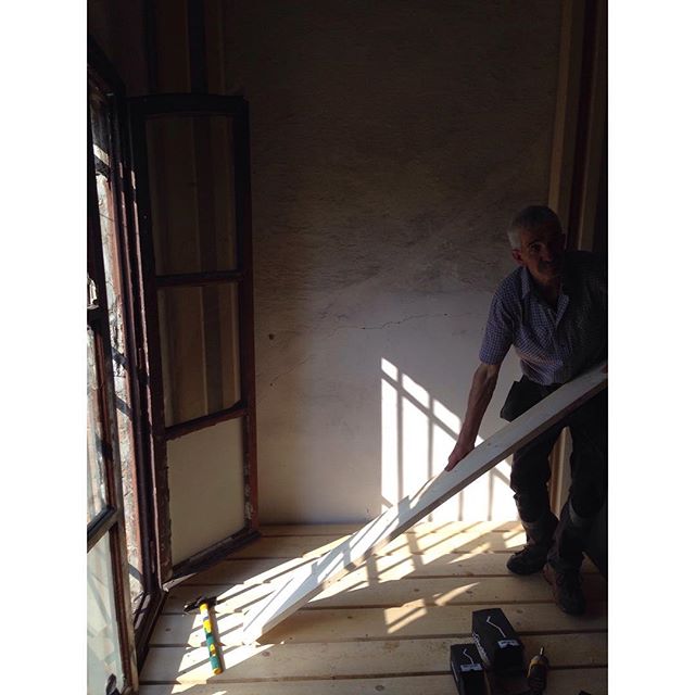A man is working with wood planks indoors, as part of a home renovation or construction project.