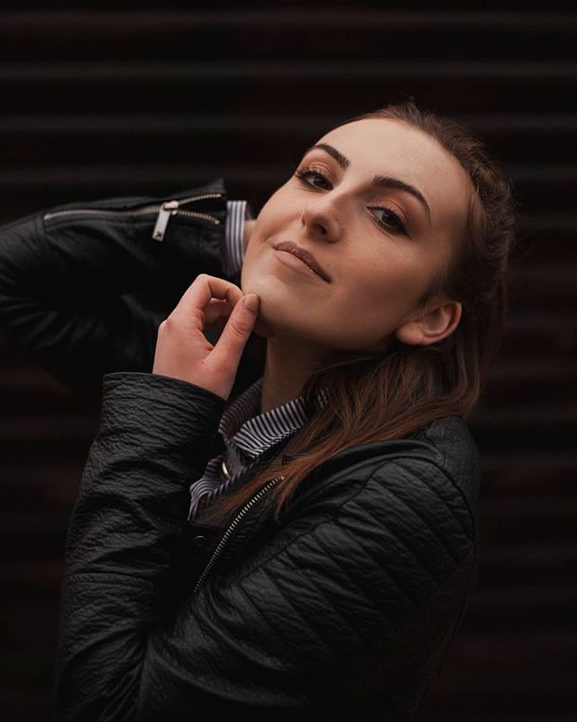 A confident woman in a leather jacket poses outdoors with soft, natural lighting, perfect for fashion or beauty campaigns.
