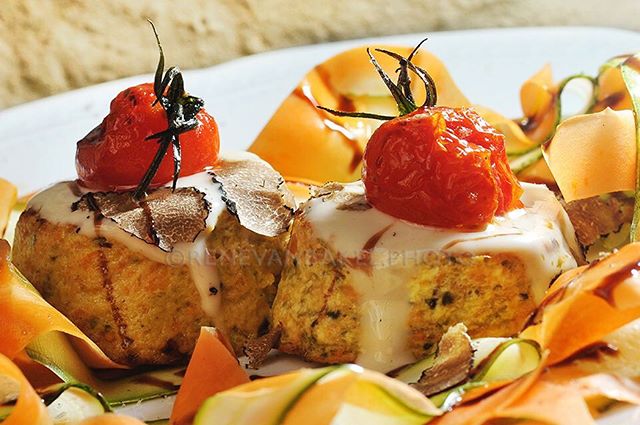 Elegant dish with tomatoes, truffles, and creamy sauce, beautifully plated with vegetable ribbons.