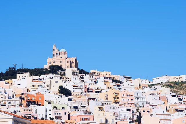 Scenic view of a hillside town featuring traditional architecture and a prominent church under a bright blue sky.