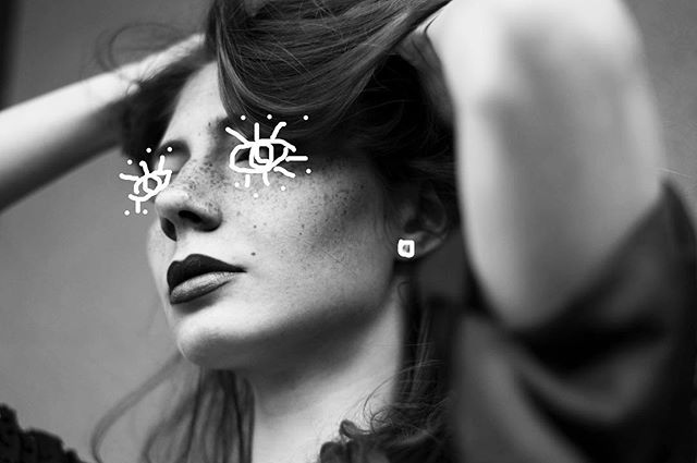 Black and white portrait of a woman with freckles in a moody, editorial style.