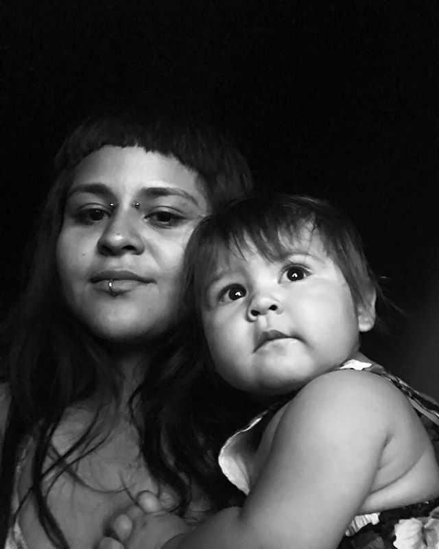 A black and white portrait of a mother holding her baby close with a soft and loving expression.