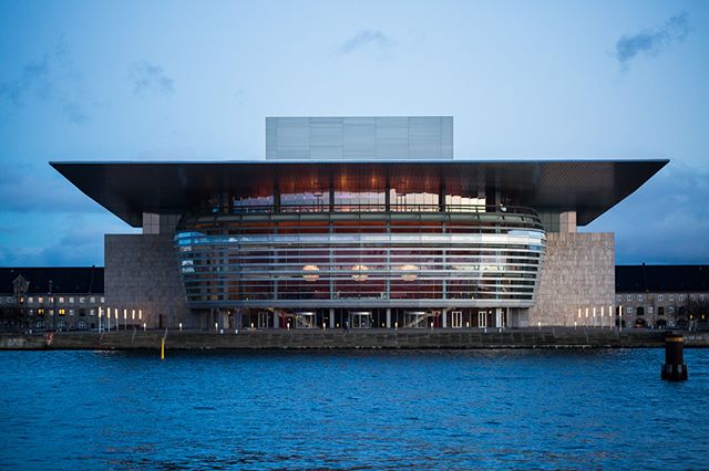 The Copenhagen Opera House is a modern architectural landmark on the waterfront, captured in a tranquil outdoor setting.
