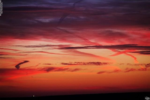 A vibrant sunset sky with contrails creating a beautiful and colorful scene.