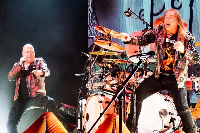 A rock band performs live on stage, with a singer and drummer energizing the audience at a concert.