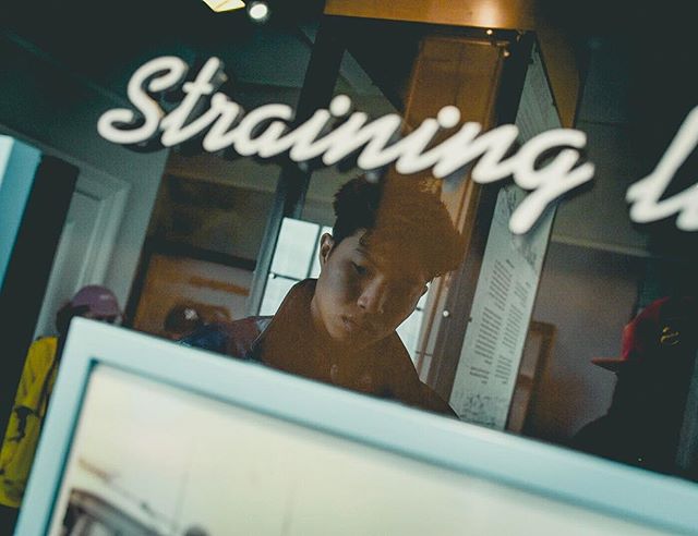 A person looks at a museum exhibit, reflected in glass with signage, for an insightful cultural experience.