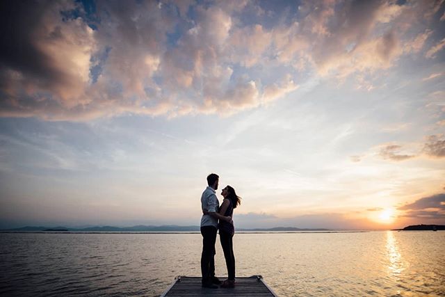 A couple stands silhouetted on a pier at sunset, embracing the romance of a peaceful evening by the lake.