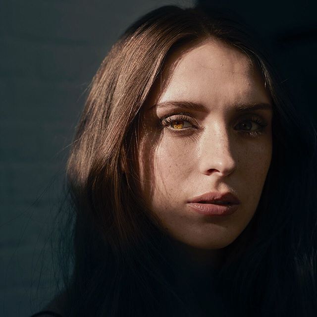 A close-up portrait of a brunette woman with fair skin in soft, natural light, emphasizing beauty and authenticity.