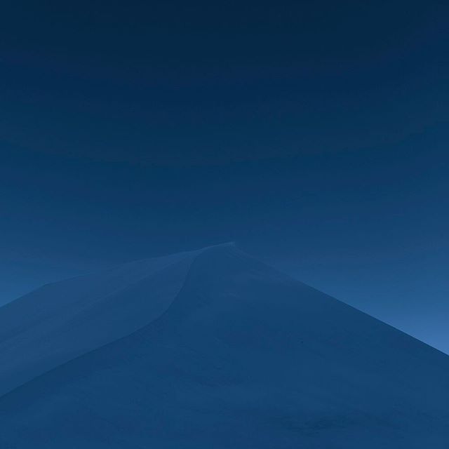 A serene, monochromatic landscape featuring a smooth dune under a soft blue sky, perfect for a calming background.