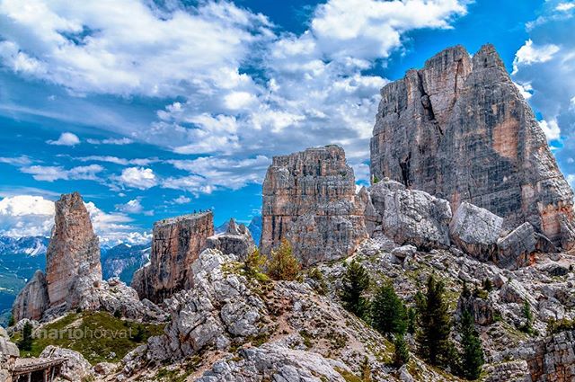 Scenic view of rocky mountain peaks under a blue sky with white clouds in the Dolomites.