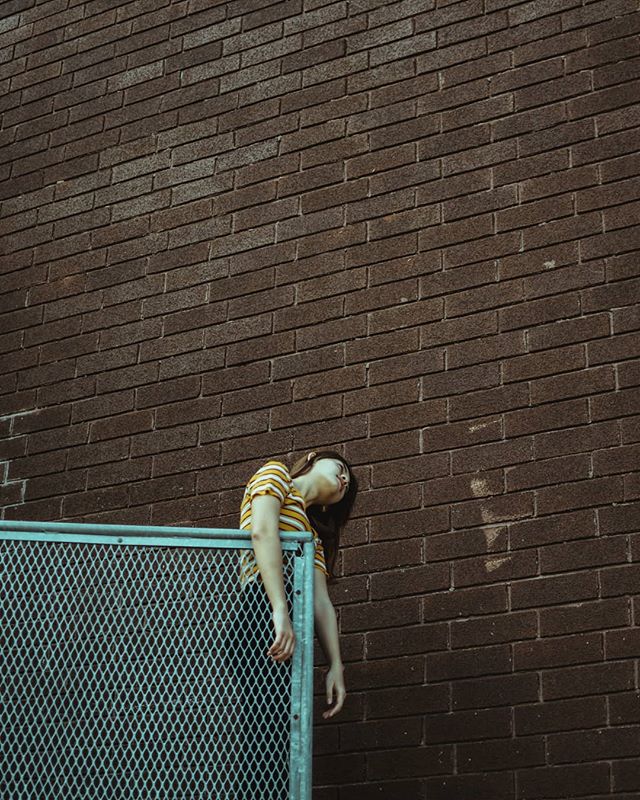 A young woman leans over a railing in an urban setting, conveying a sense of emotional intensity and introspection.