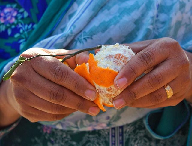 Close-up of hands peeling an orange, emphasizing natural textures and a warm, inviting mood.