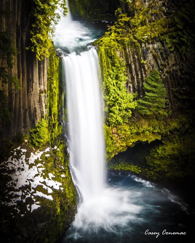 A scenic waterfall cascades down mossy rocks in a tranquil forest setting. Perfect for nature and travel themes.