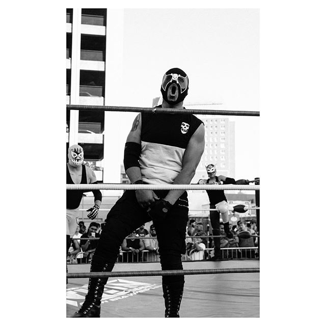 A black and white photo of wrestlers in a ring, with one wrestler in focus and crowd in the background.
