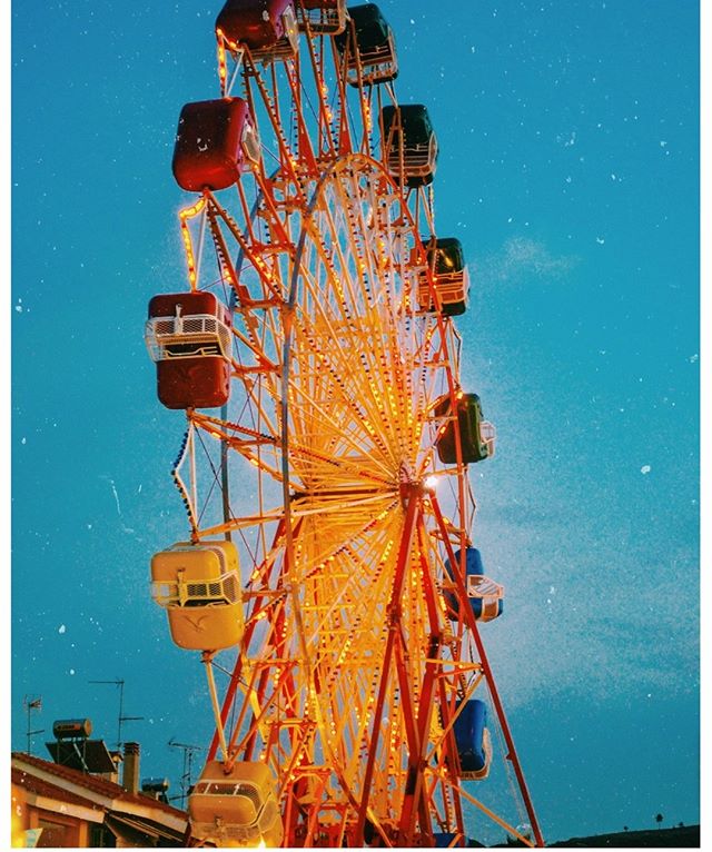 A vintage ferris wheel stands tall against a twilight sky, promising fun and excitement at the amusement park.