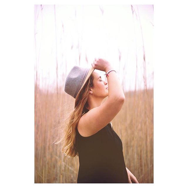 Woman in a hat enjoys a peaceful moment in a field, bathed in warm, soft light.