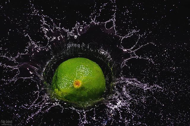 A vibrant lime splashes into water, captured against a dramatic black backdrop in this refreshing studio shot.
