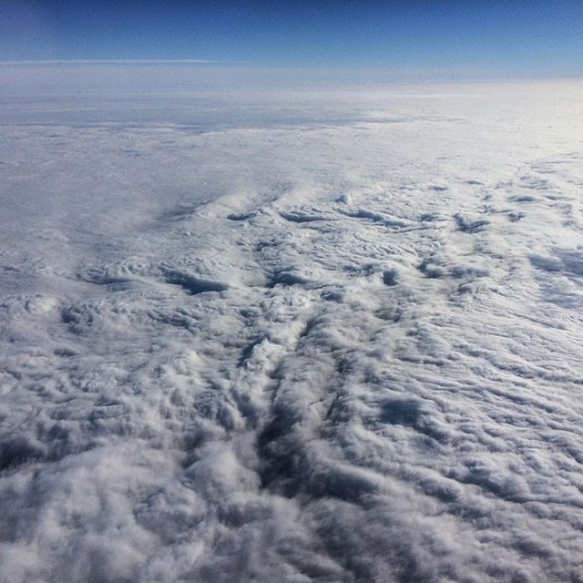 An aerial view showcases a thick cloud layer below a clear blue sky, perfect for travel or scenic backgrounds.