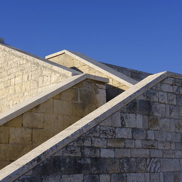 Architectural shot of stone stairs against a clear blue sky, highlighting modern design and construction.