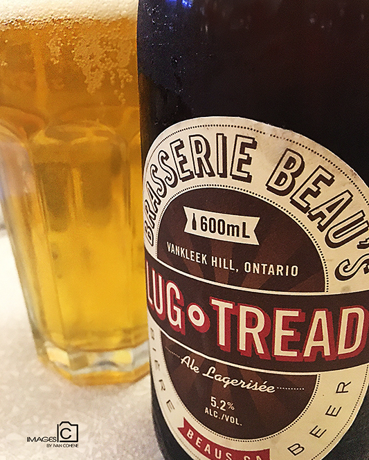 A close-up of a Brasserie Beau's beer bottle and glass with golden beer.
