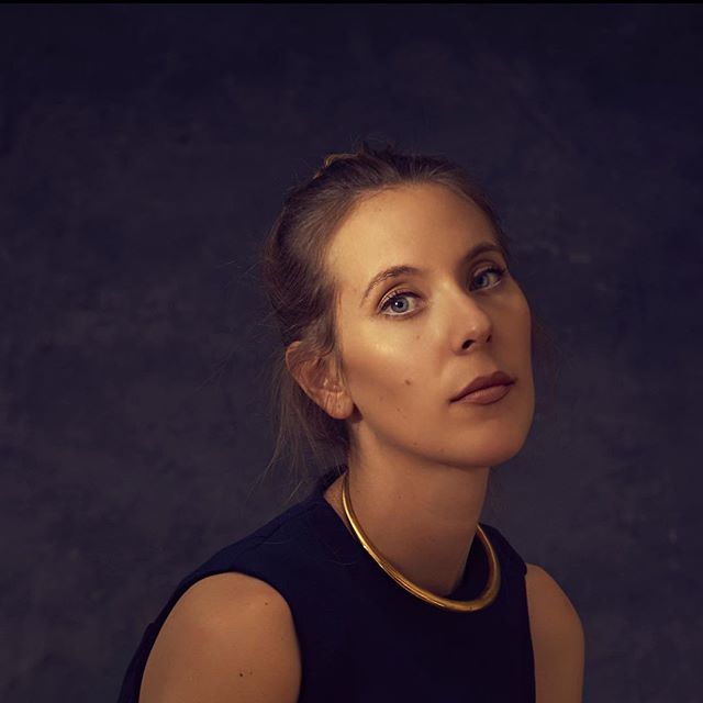 A stylish woman poses in a studio setting with soft lighting for a fashion editorial.