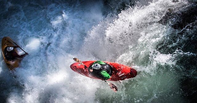 Two kayakers navigate the intense rapids of a churning river in an action shot.